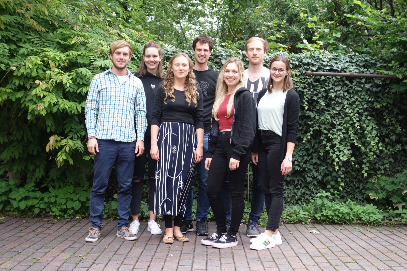 Das ehrenamtliche Team von Watoto wa Nest e.V. steht vor grünen Büschen